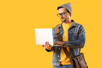 Young man using laptop on yellow background