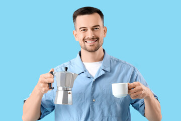 Handsome man with geyser coffee maker and cup of espresso on blue background