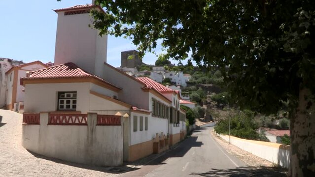 Small old houses renovated and painted white and yellow on the hillside, with Castelo de Vide in the background
