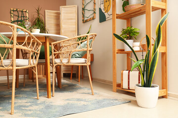 Interior of cozy room with plants, dining table and shelf unit