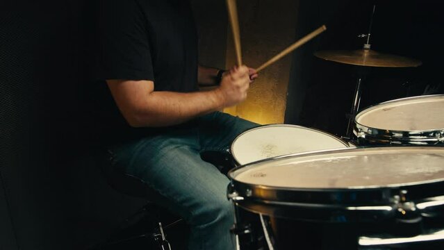 Expressive drummer young man professionally playing on dums in studio room close-up. Rock metall music artist 