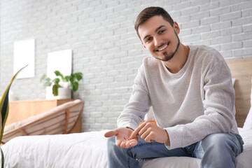 Young man with pill organizer in bedroom