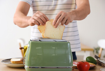 Middle-aged man making tasty toasts in kitchen, closeup