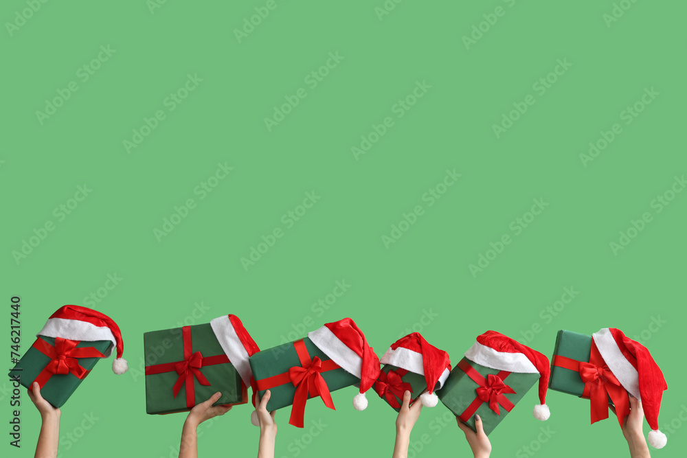 Wall mural Female hands holding Christmas gift boxes on green background