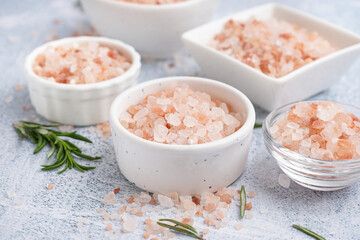 Bowls with Himalayan pink salt and rosemary on white background