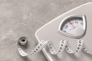 Scales with white measuring tape on grey background