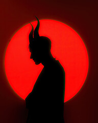 silhouette of a devil with horns on red circle background
