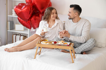 Young couple having breakfast in bed on Valentine's Day