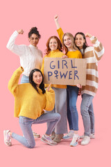 Obraz premium Beautiful young happy women holding paper with text GIRL POWER and showing muscles on pink background. Women history month