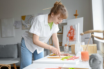 Female artist painting flowers at table in workshop