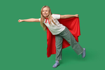 Cute teenage girl dressed as superhero on green background