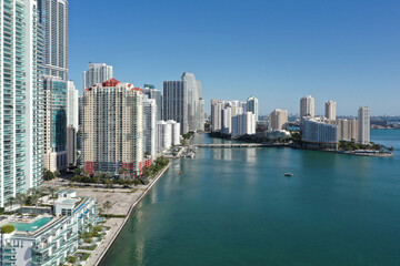 Naklejka premium Aerial image of waterfront residential buildings in Brickell neighborhood of Miami, Florida reflected in calm water of Biscayne Bay on sunny morning.