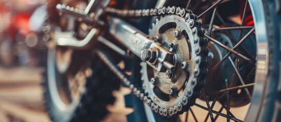A detailed close-up view of a motorcycles rear tire, chain, and brake disk. The tire tread, chain links, and metal brake components are clearly visible, showcasing the intricate details of the