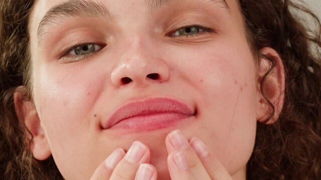 Beauty shot of woman applying foundation bb cream on previously applied moisturizing face lotion and smiling in camera. Concept of skincare, cosmetics, make up, beauty