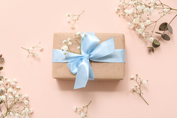 Beautiful wrapped gift box and flowers on beige background