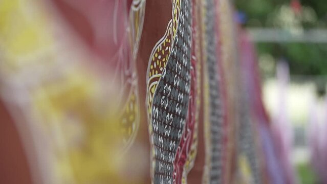 rows of batik cloth being dried in the sun blowing in the wind