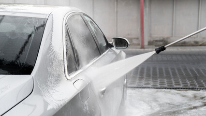 Washing luxury silver car on touchless car wash. Washing sedan car with foam self-service and high...