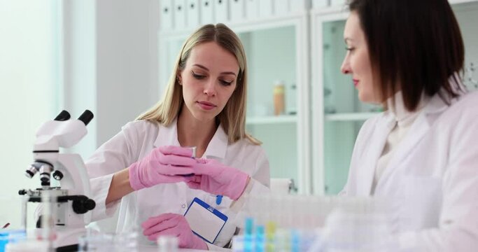 Scientist colleagues look at purple liquid in flask with solvent