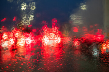This vibrant image is taken from the perspective of a driver inside a vehicle during a rainy night....