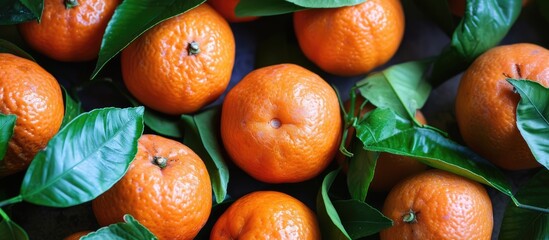 This image showcases a bunch of vibrant oranges with green leaves attached to them, creating a refreshing and luscious display. The tangerines and leaves form a visually appealing medley, highlighting