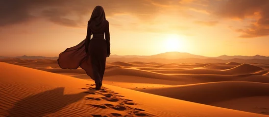 Fotobehang Silhouette view of beautiful muslim woman walking on desert sand © Media Srock