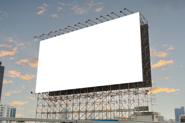 A large blank billboard stands against a blue sky with some clouds. The billboard is in a field...