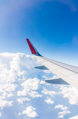 Fototapeta premium View from the airplane window at a beautiful cloudy sky and the airplane wing
