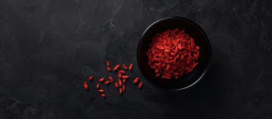 A black bowl filled with vibrant red food sits atop a wooden table. The stark contrast between the...