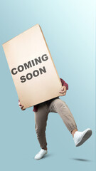 People carrying large box with with 'coming soon' text