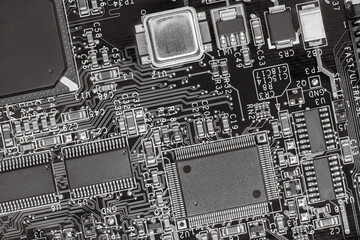 closeup of circuit board with resistors, condensers, microchips and electronic components. b/w.