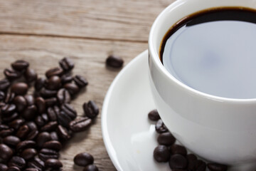 Coffee cup, coffee beans on wooden table, close up