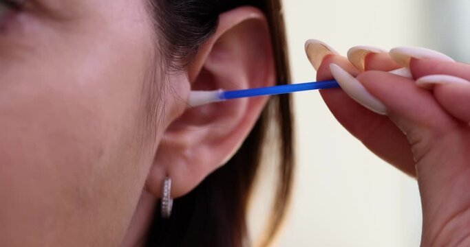 Young woman cleans ear with cotton swab