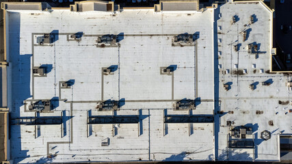 Aerial top down view of a flat roof of a large industrial building with HVAC units. Ponding dirty water spots.
