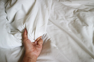 Soft focus hand of women holding bedclothes. Hand sign orgasm of woman on white bed , Hand of...