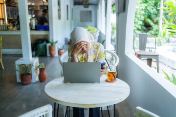 young businesswoman wearing a hijab. Sitting with a dizzy gesture or thinking. In a cafe, work anywhere. - obrazy, fototapety, plakaty