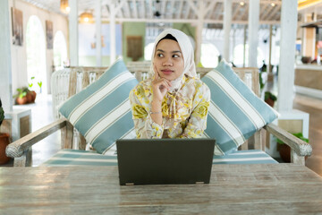 young businesswoman wearing a hijab. Sitting with a dizzy gesture or thinking. In a cafe, work...