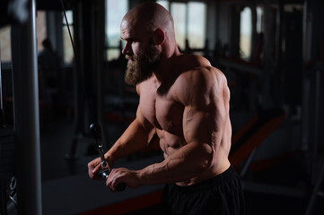 Barechested man with a beard is working out in a gym