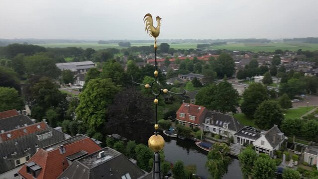 Aerial view orbiting ornate metal cockerel weather vane lightning conductor cross overlooking charming Dutch village