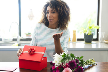 Biracial woman presents a gift at home during an online date video call