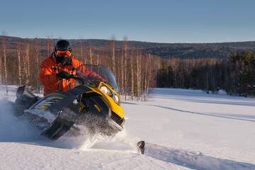 Athlete on a snowmobile moving in the winter forest in the mountains of the Southern Urals