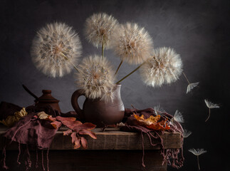 Modern still life with large dandelions in a clay jug on a dark background