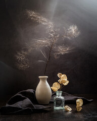 Modern still life with dried plants in a vase on a dark background. Wind and movement in the frame