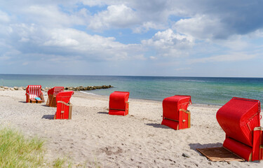 Traditional German roofed wicker beach chairs on the beach of Baltic Sea. Beach with red chairs on...