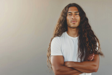 A man with flowing long hair crossed arms and a relaxed stance. - obrazy, fototapety, plakaty