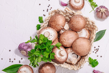 Obraz na płótnie Canvas Raw brown royal champignons in the basket. Cooking vegan food concept. Garlic, greens, spices