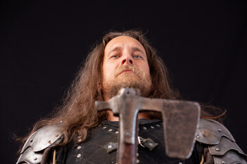 Close-up portrait of a medieval knight with an axe on a black background