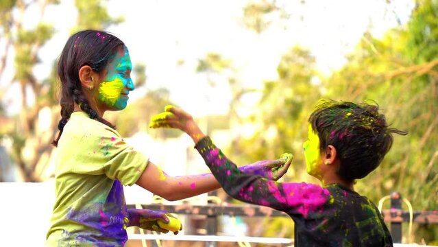 Happy Cute Indian kids applying colours on each other on the occasion of colors festival holi