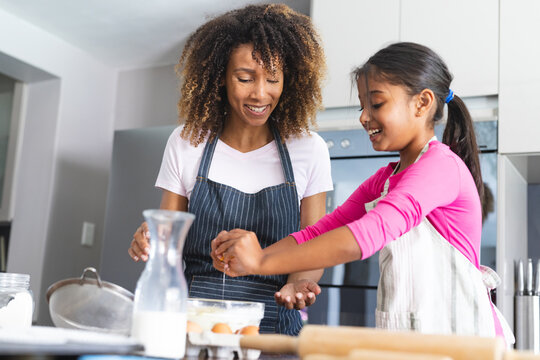 Biracial mother and daughter enjoy baking together at home for daughter