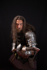 Vertical composition. Medieval knight in shining armor with spear on black background