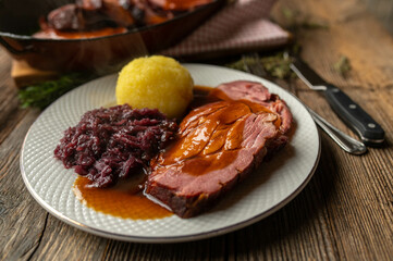Plate with slices of roast pork, potato dumpling, red cabbage and a delicious sauce
